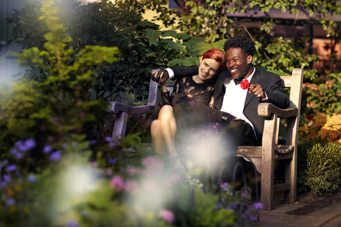Glückliches Paar sitzt auf einer Bank im Park - CAVF40438