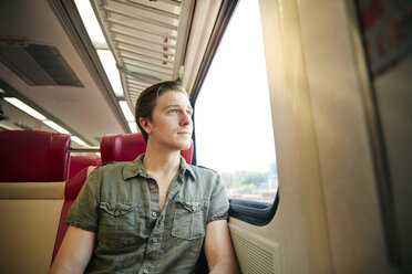 Mann schaut durch ein Fenster während einer Zugfahrt - CAVF40453