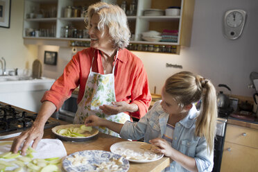 Woman with granddaughter arranging apple slices in plate - CAVF40485