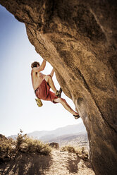 Low angle view of shirtless Wanderer Klettern Felsen gegen klaren Himmel - CAVF40605