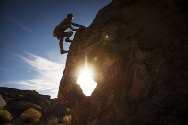 Silhouette man climbing rock formation against sky - CAVF40611