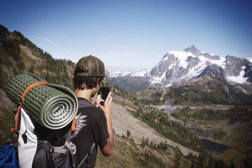 Wanderer, der mit seinem Smartphone Berge gegen den Himmel fotografiert - CAVF40677