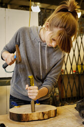 Frau beim Schnitzen von Holz mit Meißel und Hammer in einer Werkstatt - CAVF40743