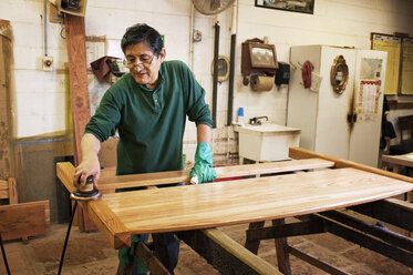 Carpenter sanding wooden plank at workshop - CAVF40758