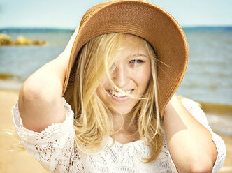 Portrait of smiling woman wearing sun hat at beach - CAVF40772