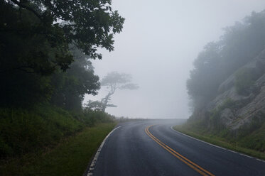 Leere Straße inmitten von Bergen gegen den Himmel bei nebligem Wetter - CAVF40792