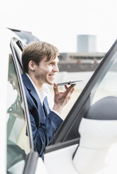 Smiling businessman using smartphone in car - UUF13414