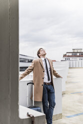 Businessman leaning back at parking garage - UUF13444