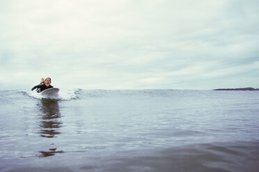 Aufgeregte junge Frau beim Surfen auf dem Meer vor bewölktem Himmel - CAVF40807