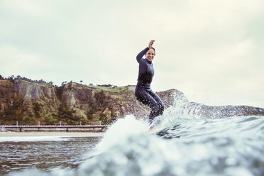 Porträt einer glücklichen Frau beim Surfen auf dem Meer vor bewölktem Himmel - CAVF40808