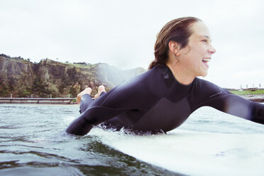 Glückliche Frau auf Surfbrett im Meer liegend gegen Himmel - CAVF40810