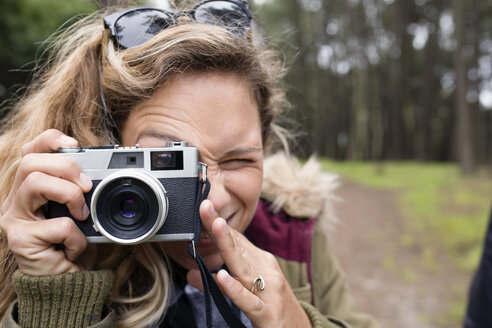 Nahaufnahme einer Frau, die durch eine Kamera im Wald fotografiert - CAVF40814