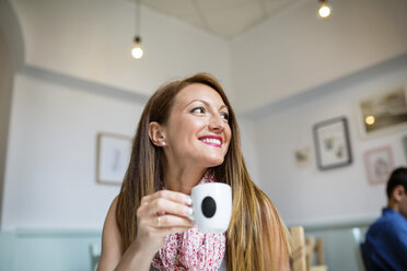 Glückliche Frau schaut weg und hält eine Kaffeetasse in einem Café - CAVF40832