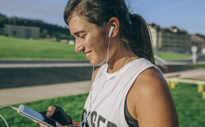 Side view of woman using phone at park - CAVF40853