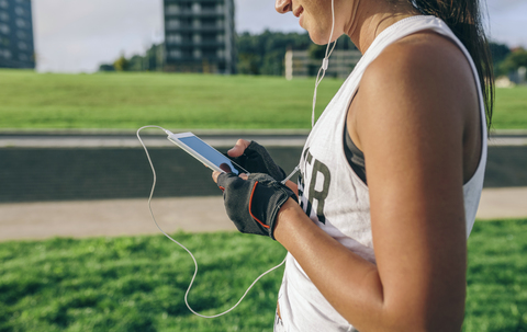 Mittelteil einer Frau, die beim Sport im Park telefoniert, lizenzfreies Stockfoto