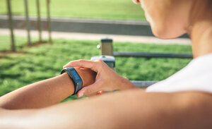 Ausgeschnittenes Bild einer Frau, die auf ihre Smartwatch schaut, während sie im Park trainiert - CAVF40857