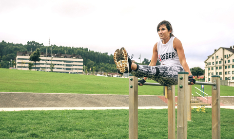 Frau in voller Länge bei Übungen am Barren im Park, lizenzfreies Stockfoto