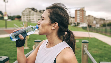 Frau trinkt Wasser während sie im Park trainiert - CAVF40877