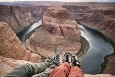 Low section of couple sitting on mountain by Horseshoe Bend - CAVF40923