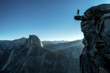 Niedriger Blickwinkel auf einen Mann, der auf einem Berg im Yosemite-Nationalpark steht, gegen einen klaren blauen Himmel - CAVF40933
