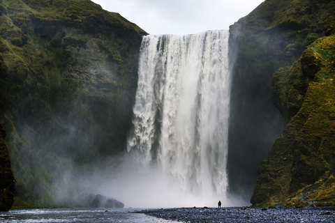 Entfernte Ansicht eines Mannes, der vor einem Wasserfall steht, lizenzfreies Stockfoto