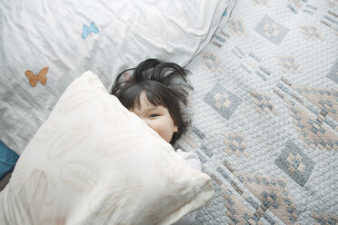 Overhead view of girl peeking over pillow at home - CAVF41254