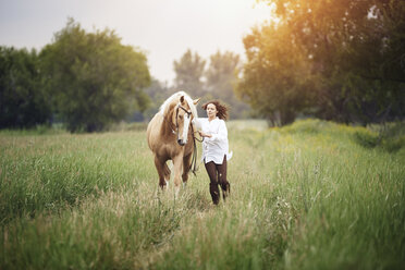 Mid erwachsene Frau und Pferd laufen auf grasbewachsenen Feld auf dem Lande - CAVF41258