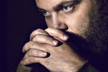 Close-up of serious man against black background - CAVF41262