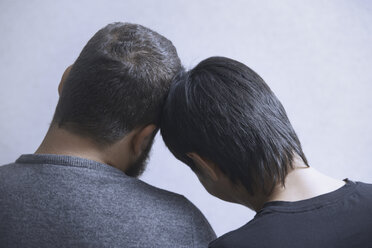 Rückansicht eines schwulen Paares, das sich an einer weißen Wand zu Hause entspannt - CAVF41279