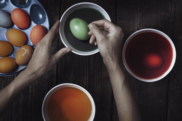 Cropped hands of woman making Easter eggs in bowl with dye at home - CAVF41283