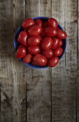 Overhead view of wet tomatoes in bowl on wooden table - CAVF41286