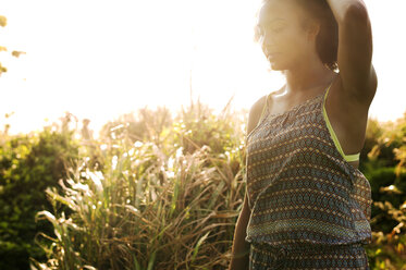 Thoughtful teenager standing against plants on sunny day - CAVF41291