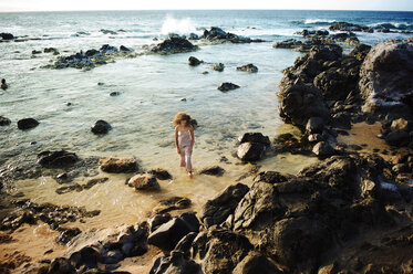 High angle view of teenager walking on rocky seashore - CAVF41299