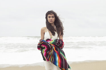 Porträt einer Frau, die eine Decke hält, während sie am Strand steht - CAVF41353