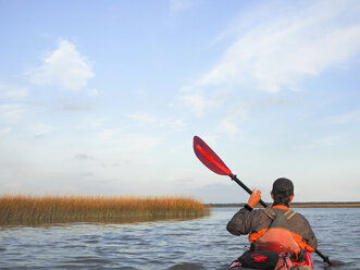 Rear view of man kayaking on lake at Cape Hatteras National Seashore against sky - CAVF41378