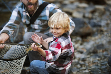 Junge hält Fisch und steht neben seinem Vater - CAVF41421