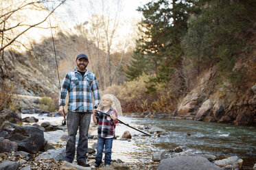 Porträt eines Vaters, der neben einem mit einem Fischernetz spielenden Jungen am Flussufer steht - CAVF41423