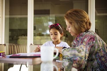 Grandmother assisting granddaughter in studying at table - CAVF41466