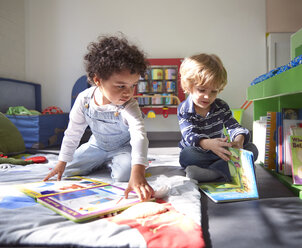 Kinder mit Bilderbüchern im Kindergarten an einem sonnigen Tag - CAVF41521