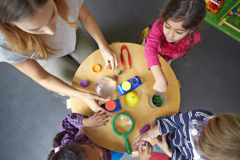 Draufsicht auf einen Lehrer, der Kindern bei einem wissenschaftlichen Experiment in der Vorschule hilft - CAVF41529