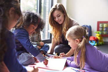 Lehrer und Schüler zeichnen in der Kinderbetreuung auf Papiere - CAVF41544