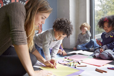 Teacher drawing with students on floor at preschool - CAVF41545