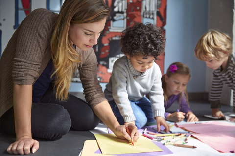 Lehrerin zeichnet mit Schülern in der Vorschule auf Papier, lizenzfreies Stockfoto