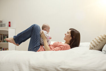 Frau spielt mit Tochter auf dem Bett liegend - CAVF41657