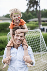 Porträt eines glücklichen Vaters, der einen verletzten Jungen auf den Schultern trägt - MASF04704