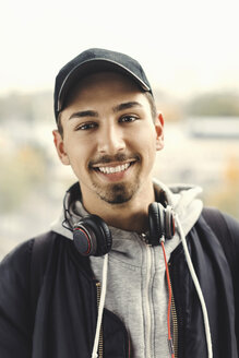 Porträt eines glücklichen Universitätsstudenten mit Kopfhörern um den Hals im Freien - MASF04728