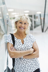 Portrait of happy businesswoman standing arms crossed in modern office - MASF04732