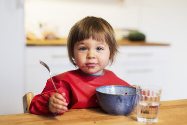 Porträt eines kleinen Mädchens mit unordentlichem Mund, das Obstsalat zu Hause isst - MASF04734