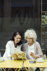 Senior women reading newspaper at outdoor cafe - MASF04748