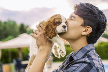 Seitenansicht eines jungen Mannes, der einen Hund im Hof küsst - MASF04756